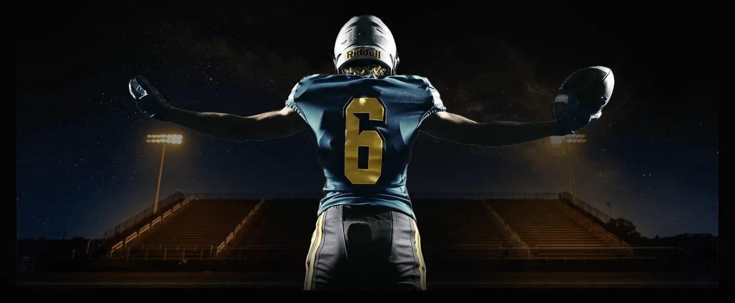 Football player facing a stadium with both arms raised